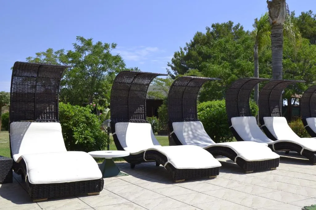 Lettini in rattan con cuscini bianchi e tettuccio nel giardino del resort