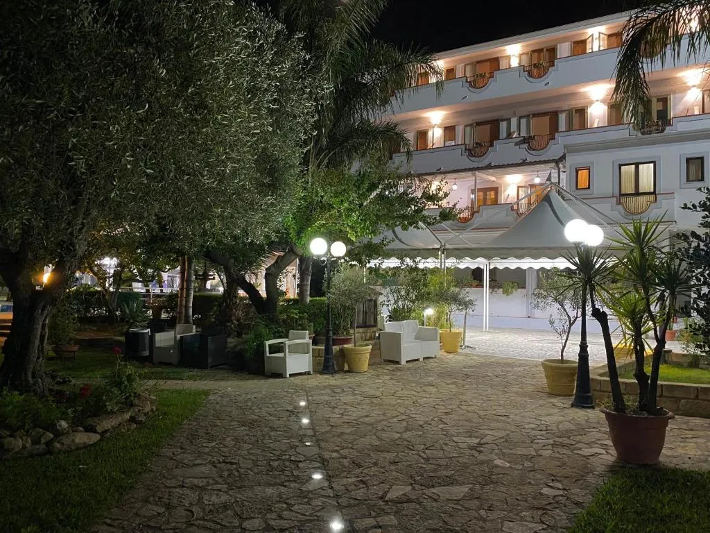 Giardino illuminato di notte con vialetto in pietra, gazebo e arredi