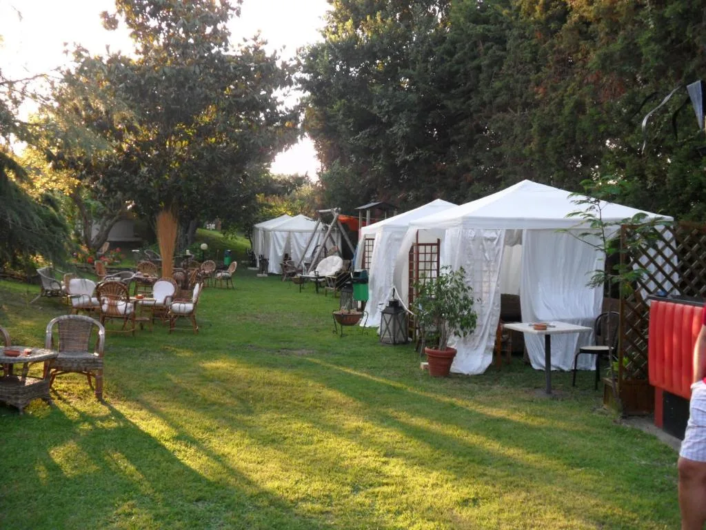 Giardino con gazebo bianchi, tavoli e poltrone in vimini al tramonto