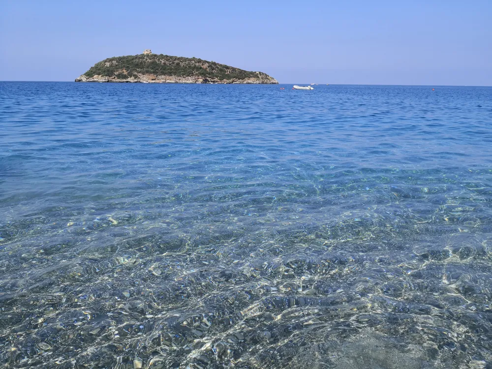 Mare limpido e trasparente con isolotto verde all'orizzonte
