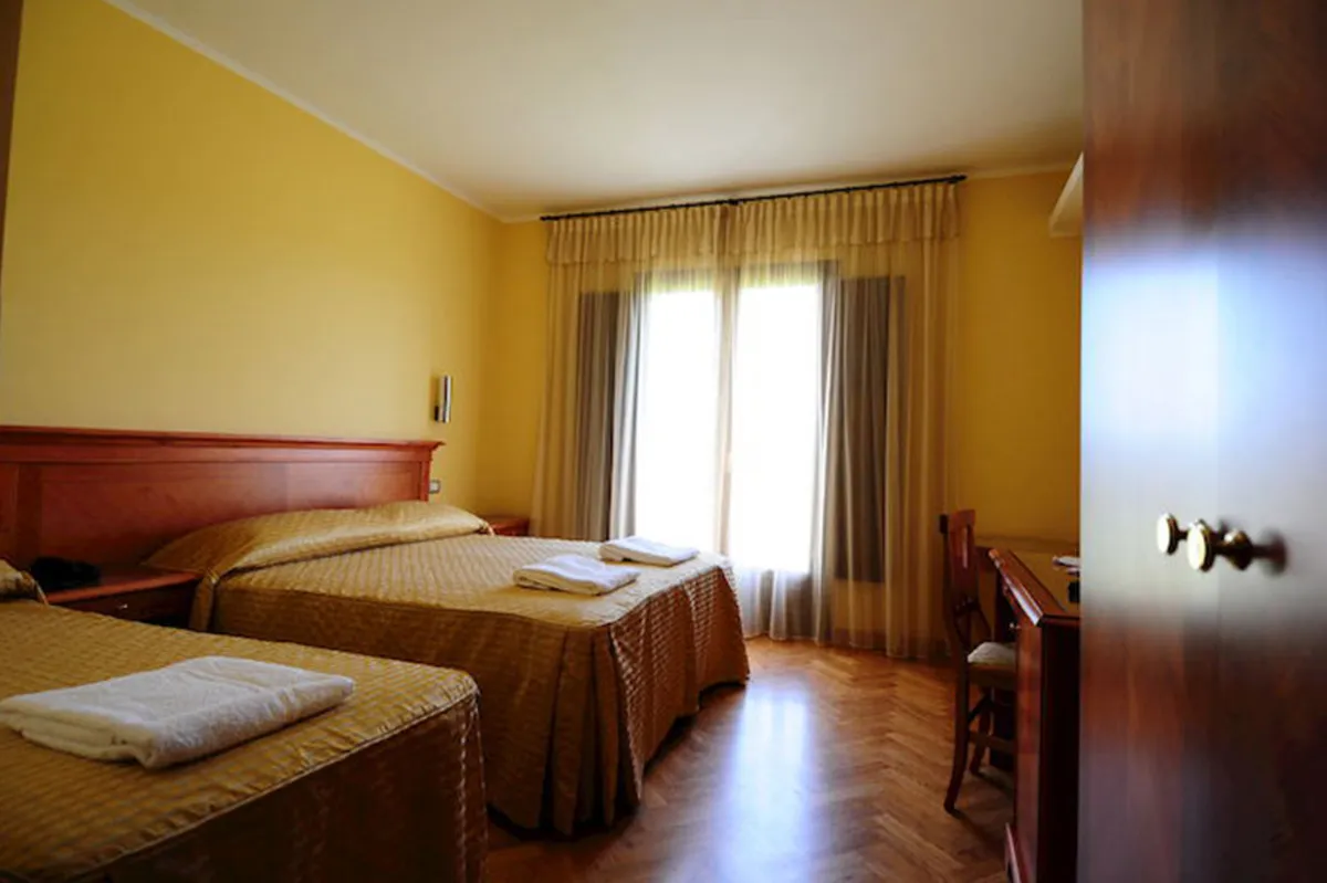 Camera con due letti, pareti gialle e pavimento in parquet