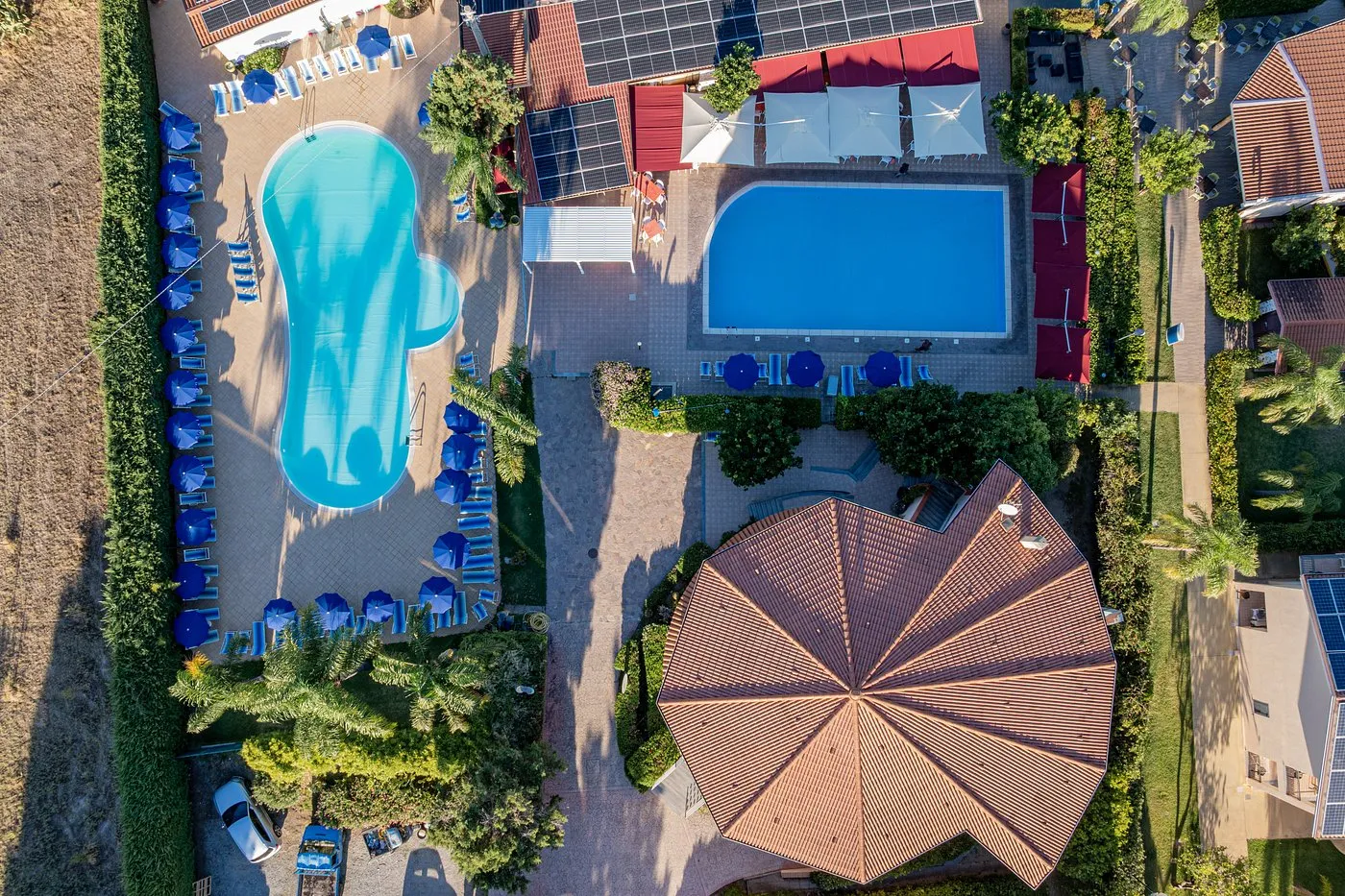 Veduta aerea di due piscine, una a forma libera e una rettangolare, con tetti in tegole