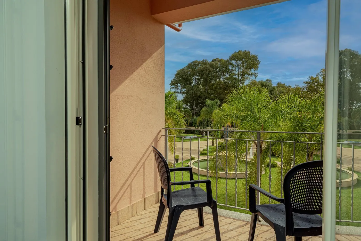 Balcone della camera con sedie e vista sul giardino e fontana