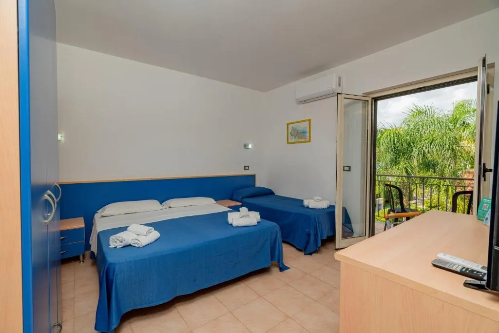 Camera con letto matrimoniale e singolo, copriletto blu e balcone