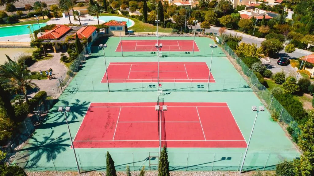 Vista aerea di tre campi da tennis in terra rossa immersi nel verde