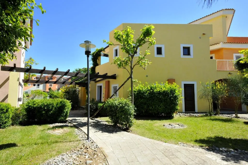 Villetta gialla con pergolato, giardino curato e vialetto pedonale