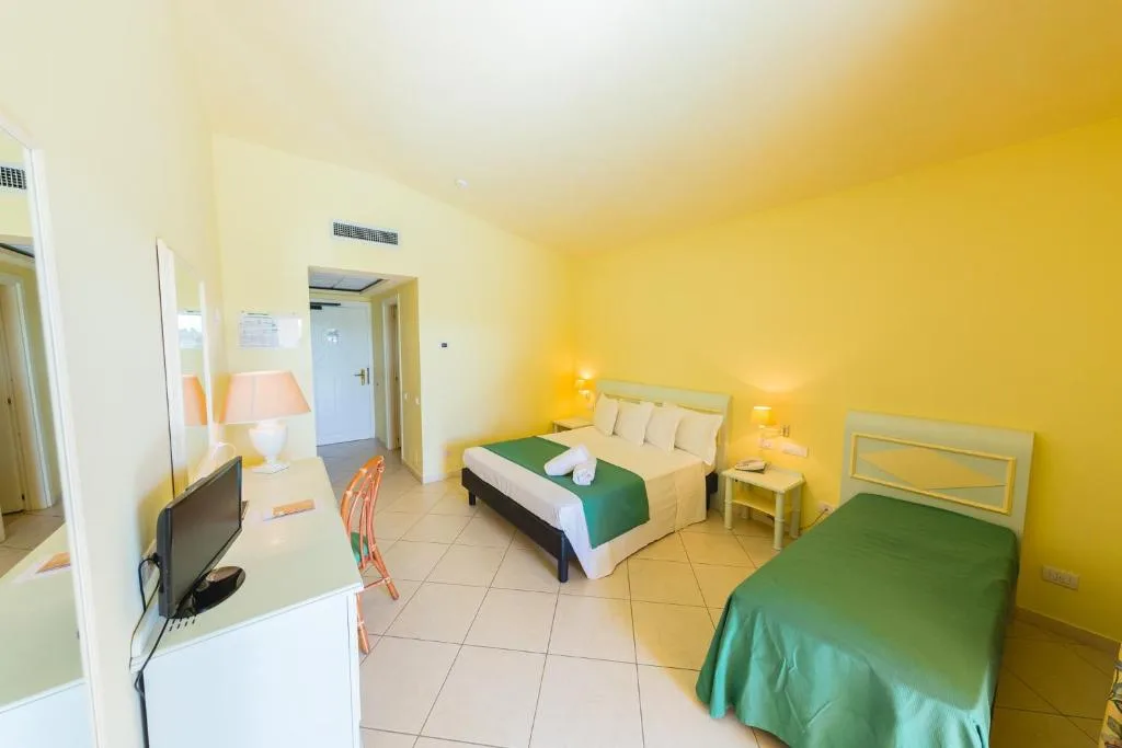 Camera con letto matrimoniale e letto singolo, pareti gialle e TV