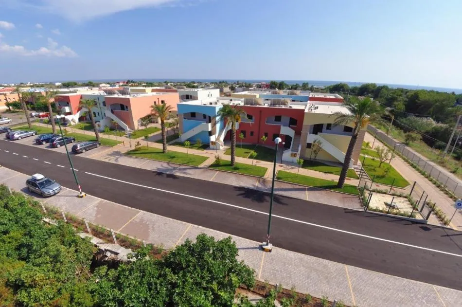 Veduta aerea del complesso residenziale colorato con strada, parcheggio e palme vicino al mare