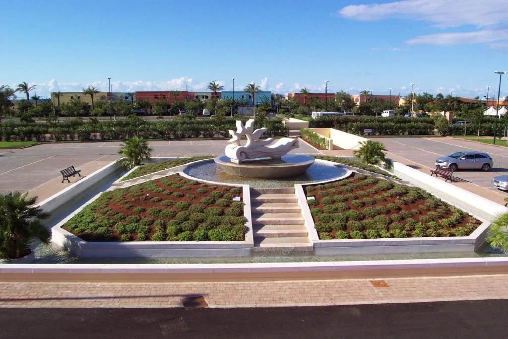 Fontana decorativa con scultura al centro di un'aiuola e parcheggio del resort
