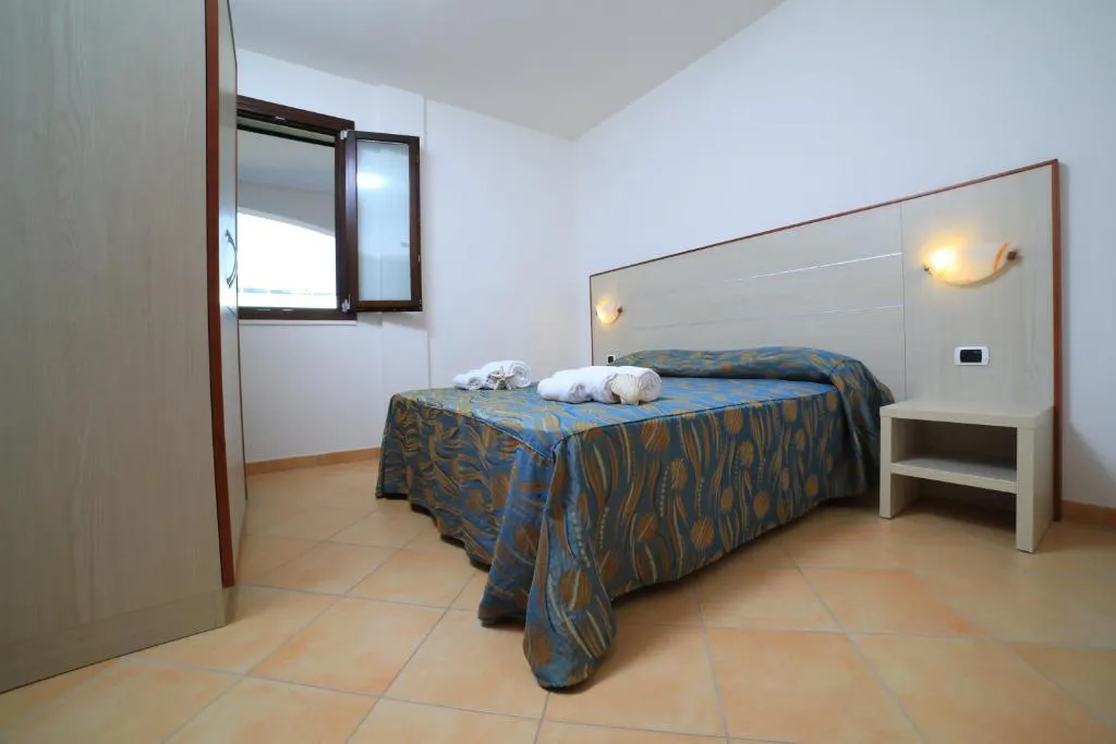 Camera da letto matrimoniale con copriletto a fantasia blu, finestra e comodino chiaro