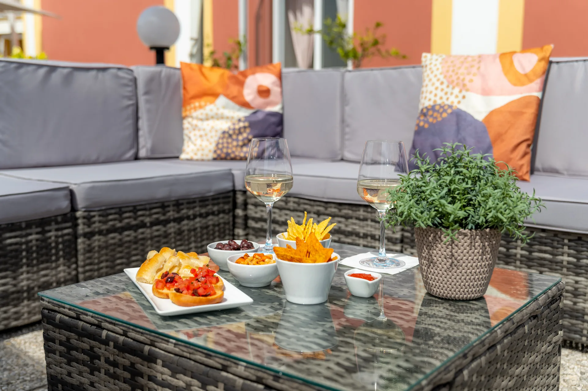 Aperitivo all'aperto con vino bianco, bruschette e stuzzichini su tavolo in rattan