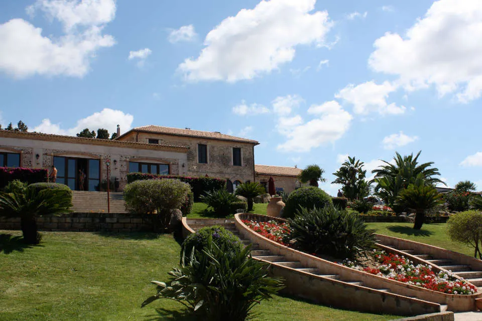 Casolare in pietra con giardino terrazzato, palme e aiuole fiorite