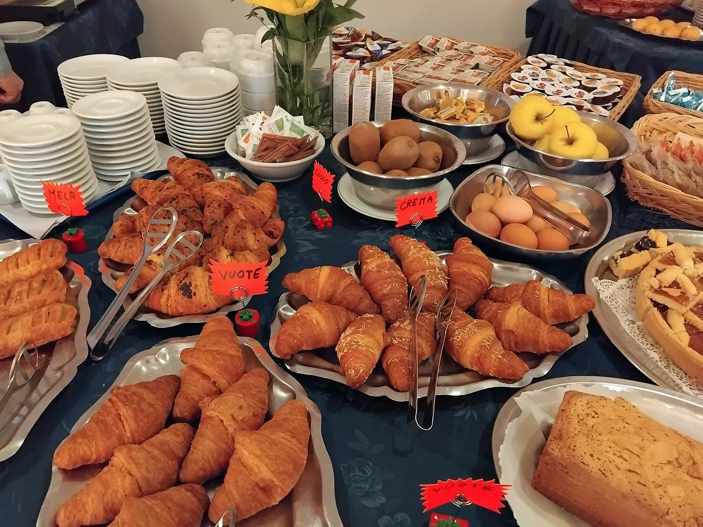Buffet della colazione con croissant, frutta fresca, uova e dolci