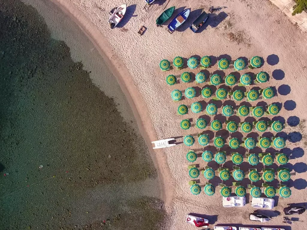 Vista aerea ravvicinata di ombrelloni verdi e gialli ordinati sulla spiaggia