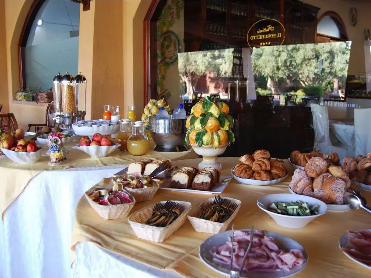 Buffet della colazione con cornetti, dolci, frutta e composizione di agrumi