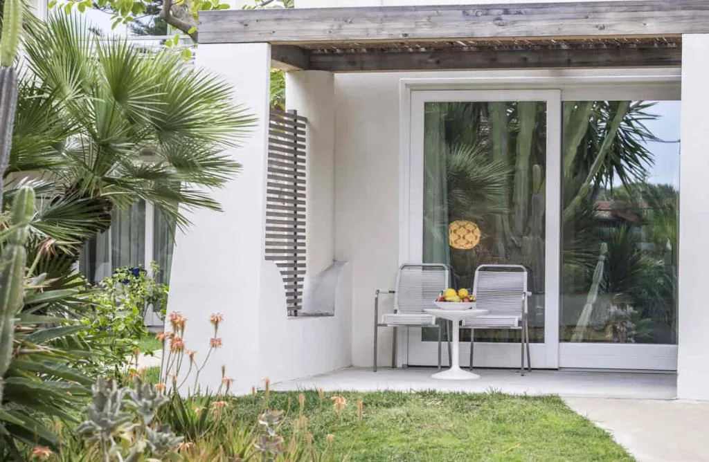 Terrazza privata di camera con tavolino, sedie e giardino con piante grasse e palme