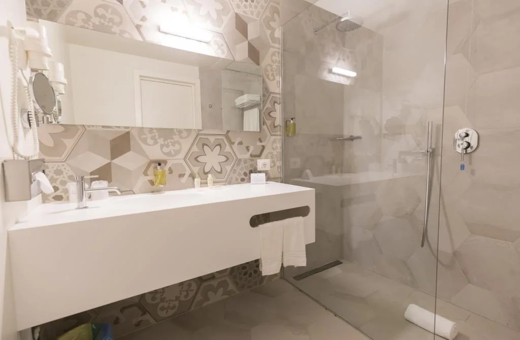 Bagno moderno con doccia a vetri, lavabo bianco e piastrelle decorate