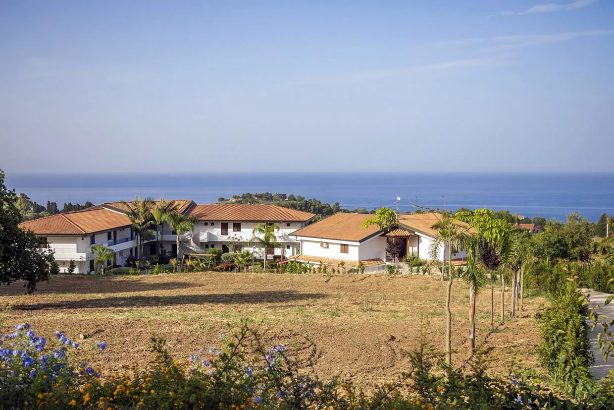 Edifici bianchi del resort con tetti rossi e vista sul mare in lontananza