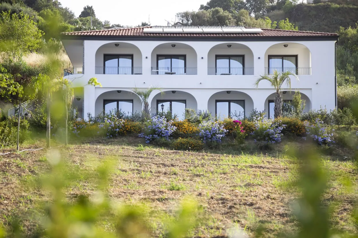 Facciata bianca dell'edificio del resort con balconi ad arco e giardino fiorito