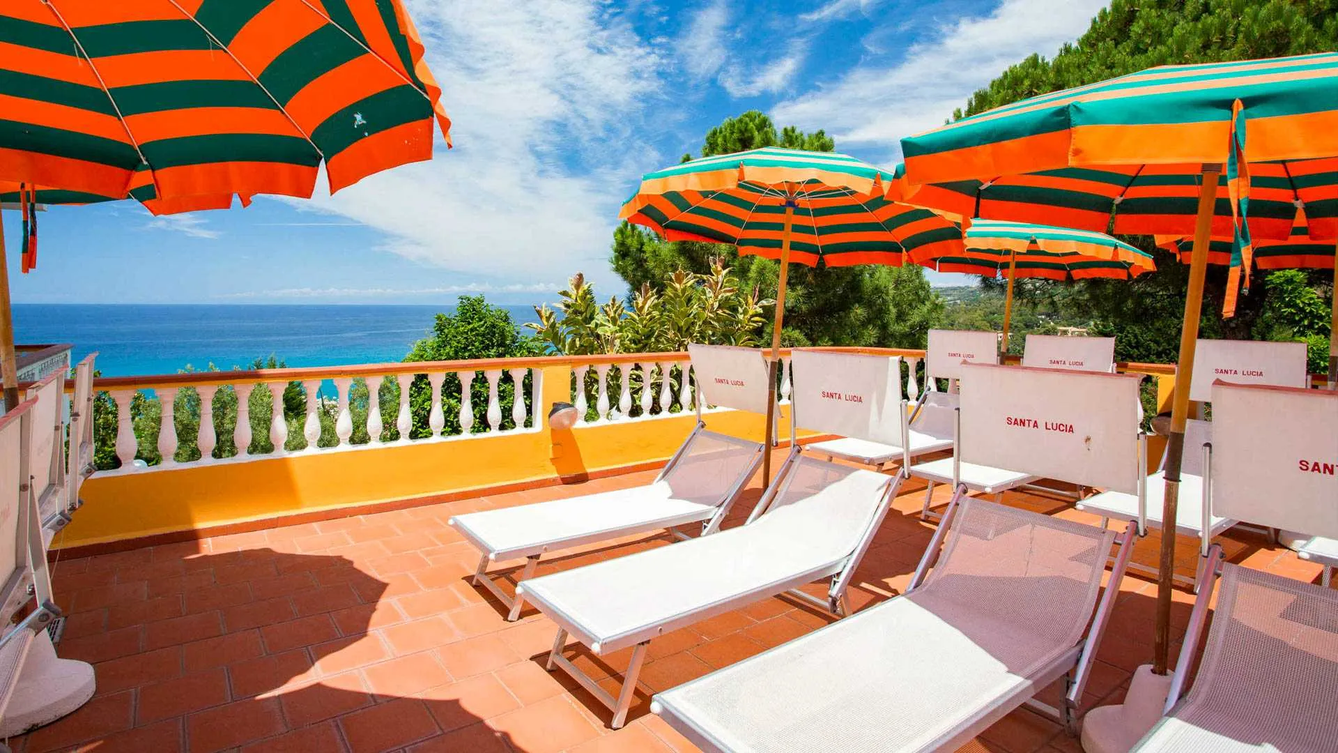 Terrazza solarium con lettini e ombrelloni a strisce affacciata sul mare