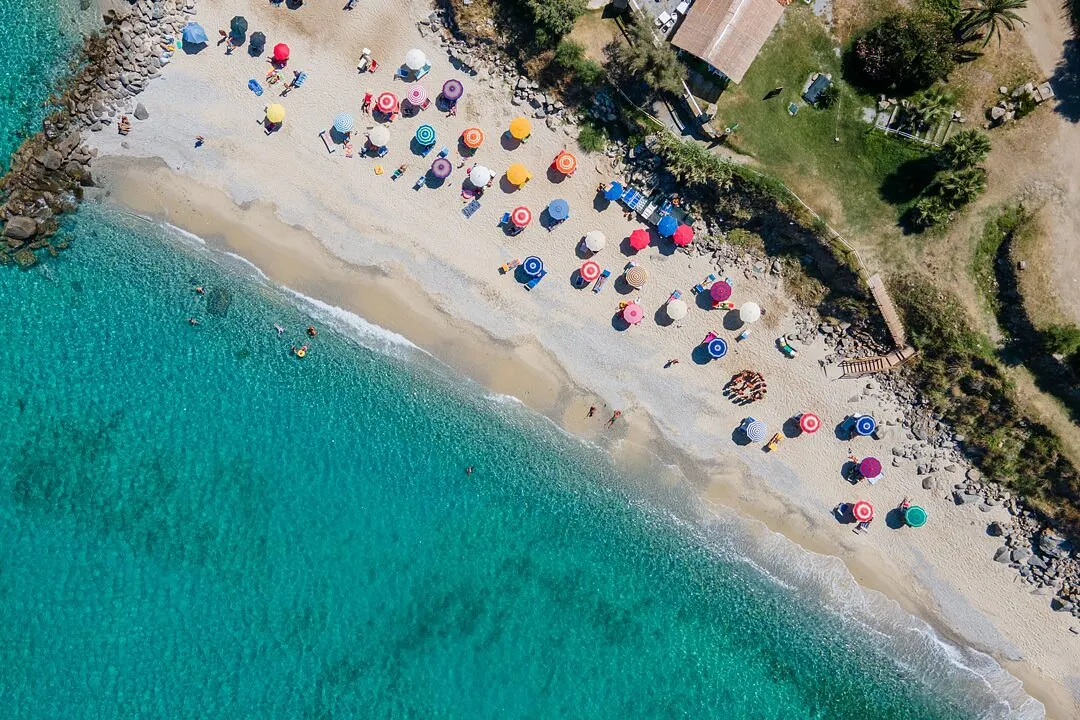 Veduta aerea della spiaggia con ombrelloni colorati e acqua trasparente