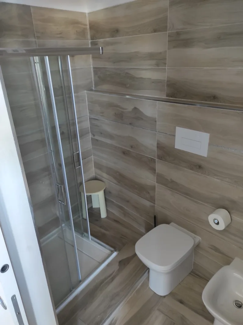 Bagno moderno con doccia in vetro e rivestimento effetto legno