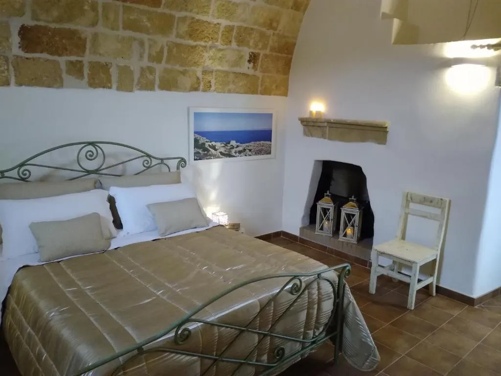 Camera con volta in pietra, letto in ferro battuto e caminetto