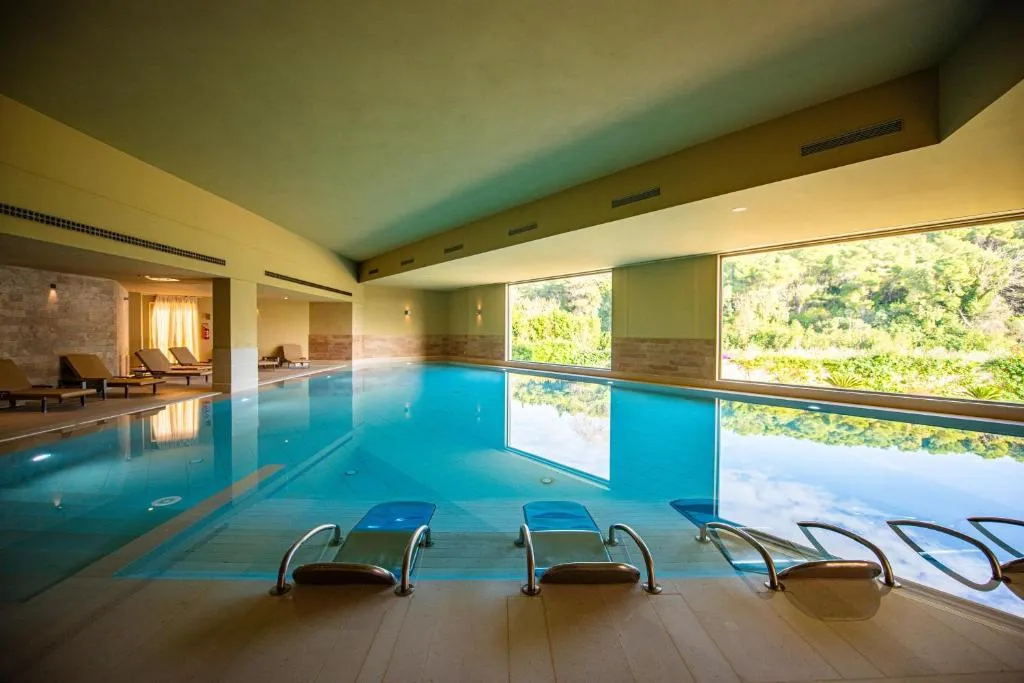 Piscina coperta con lettini e ampie vetrate affacciate sulla natura