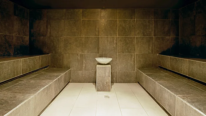 Bagno turco con pareti in pietra scura e fonte centrale