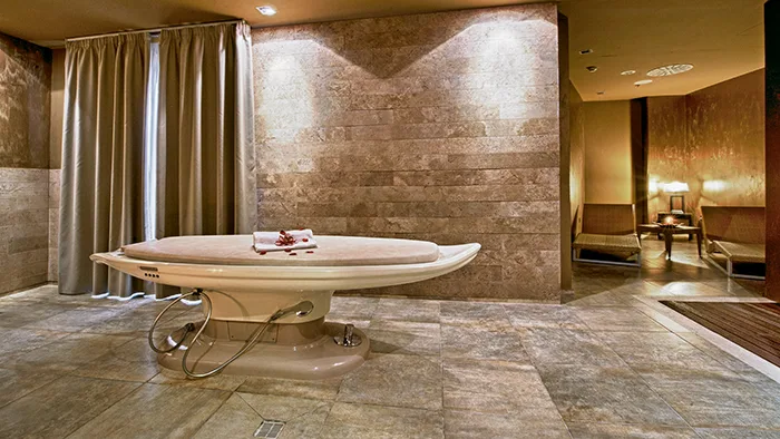 Lettino per trattamenti spa in sala con pareti in pietra