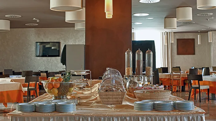 Buffet della prima colazione con frutta e dispenser nella sala ristorante