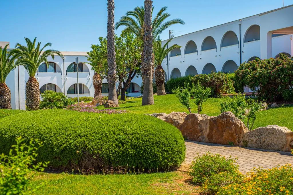 Giardino del resort con palme, siepi e edifici bianchi con archi