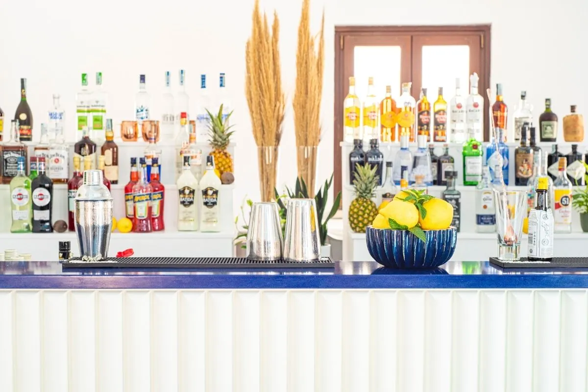 Bancone del bar con bottiglie di liquori, shaker e ciotola di limoni
