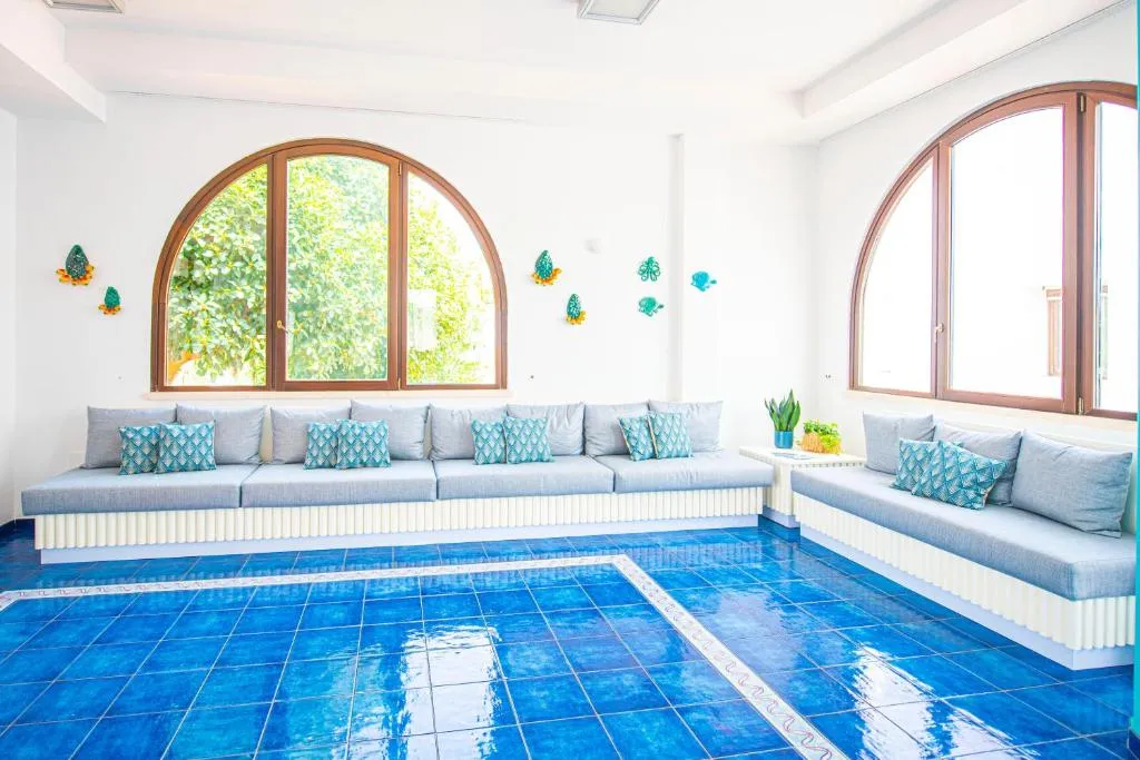 Piscina interna con pareti azzurre, divani e finestre ad arco