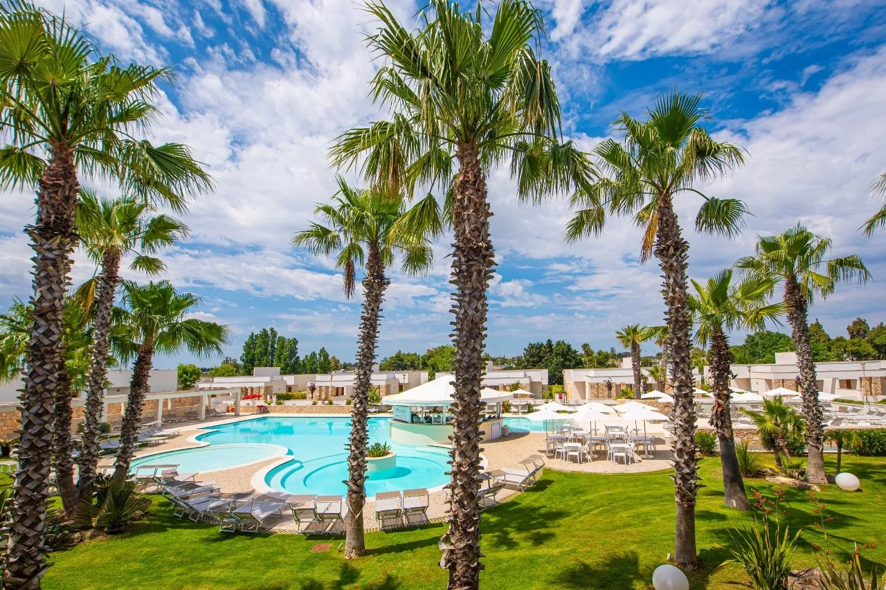Vista panoramica della piscina tra palme e prato verde curato