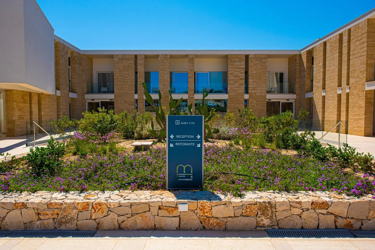 Ingresso del resort Mare Live con insegna reception e ristorante tra fiori