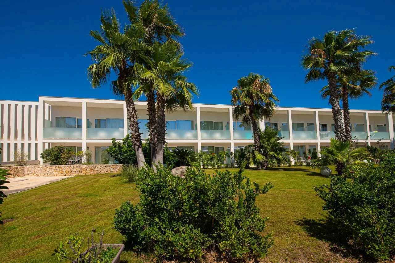 Facciata dell'hotel con palme e giardino verde