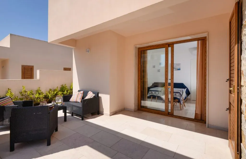 Terrazza privata con poltrone in vimini e accesso alla camera