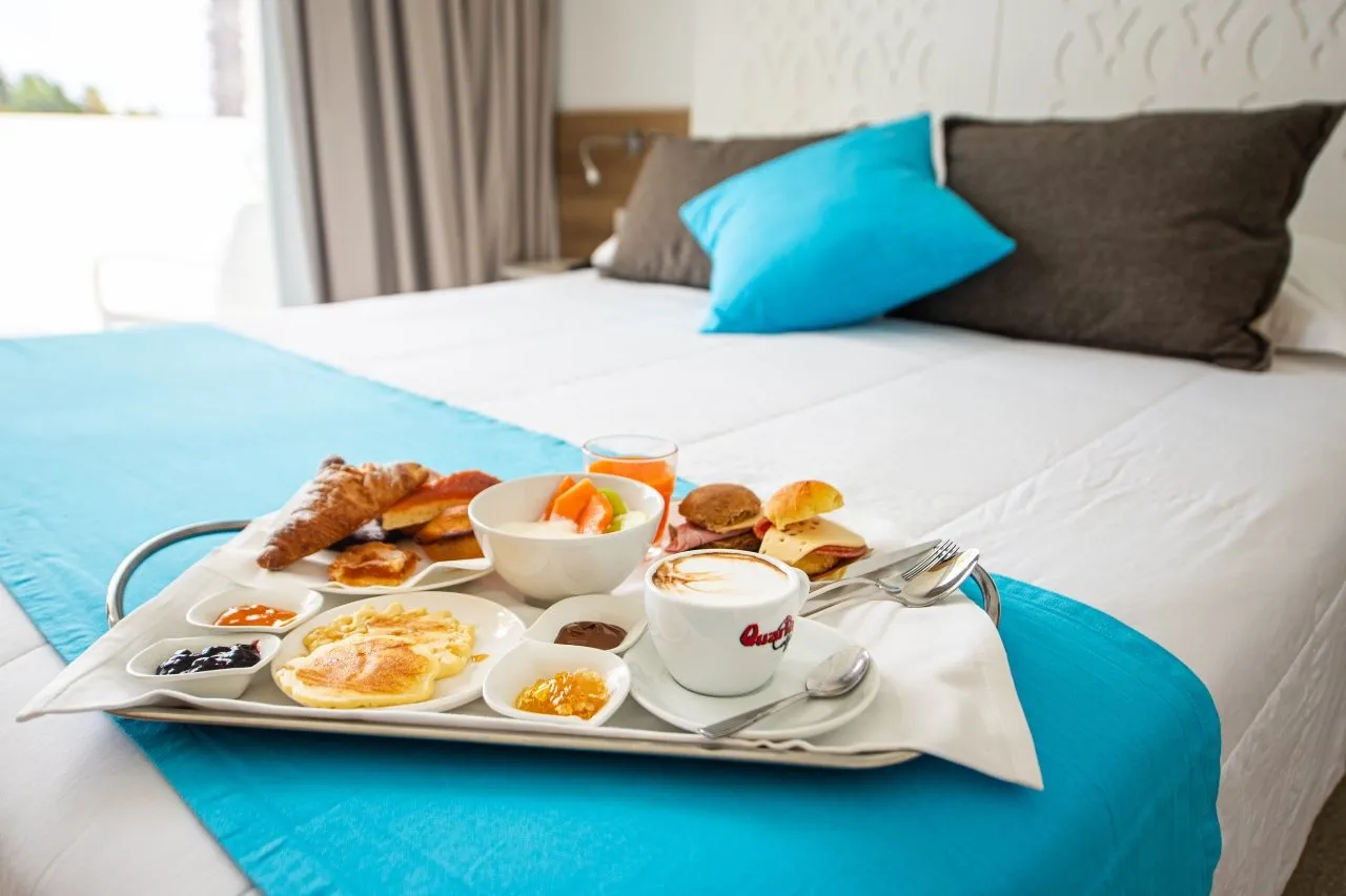 Vassoio della colazione servito sul letto con cappuccino e dolci
