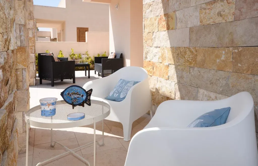 Terrazza con poltrone bianche e dettagli decorativi marini