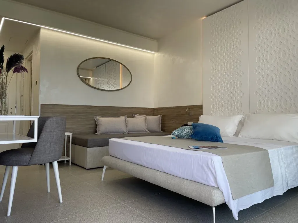 Camera elegante con letto matrimoniale, divano e specchio ovale
