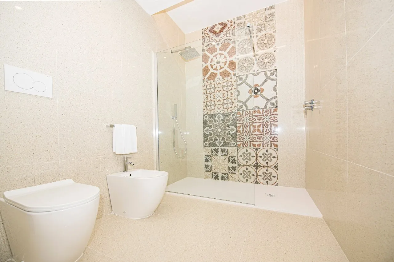 Bagno moderno con doccia, bidet e parete in piastrelle decorate