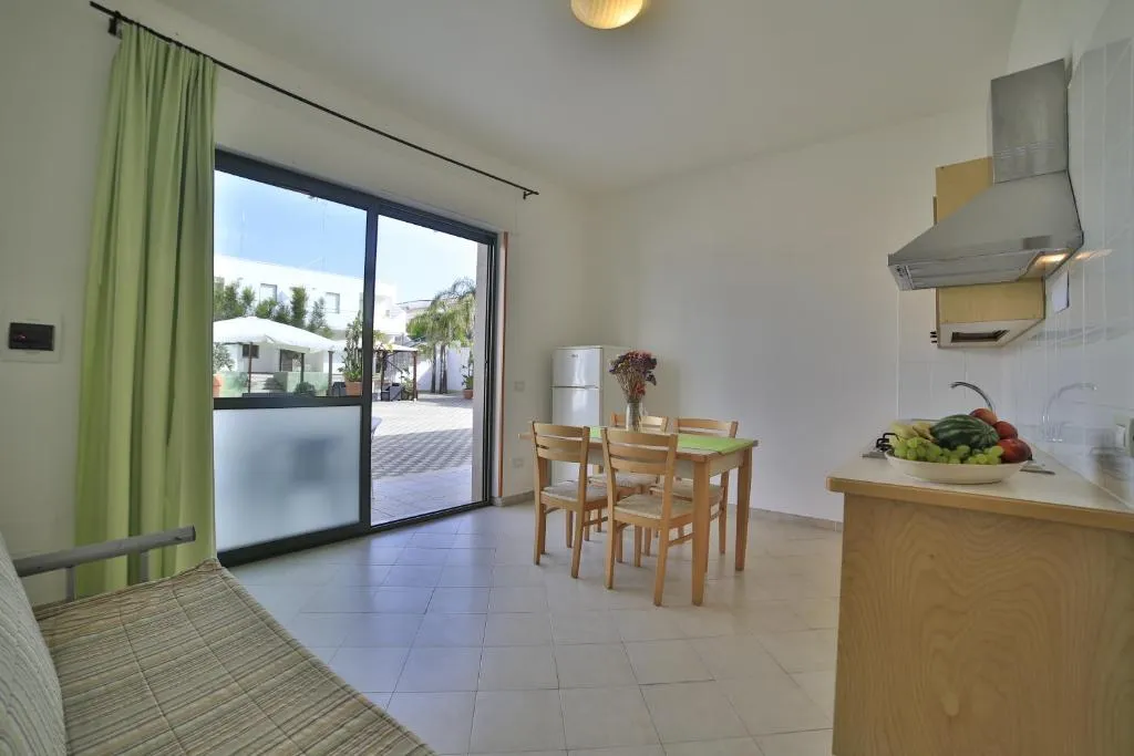 Soggiorno con cucina, tavolo e porta finestra sul cortile