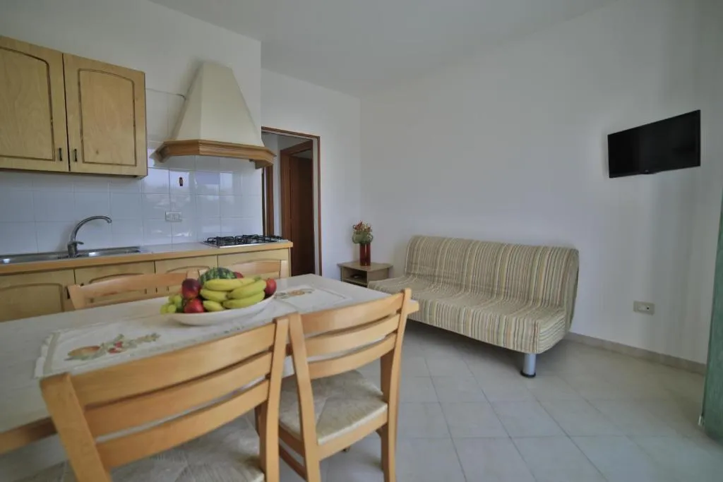 Soggiorno con cucina in legno, divano e TV a parete