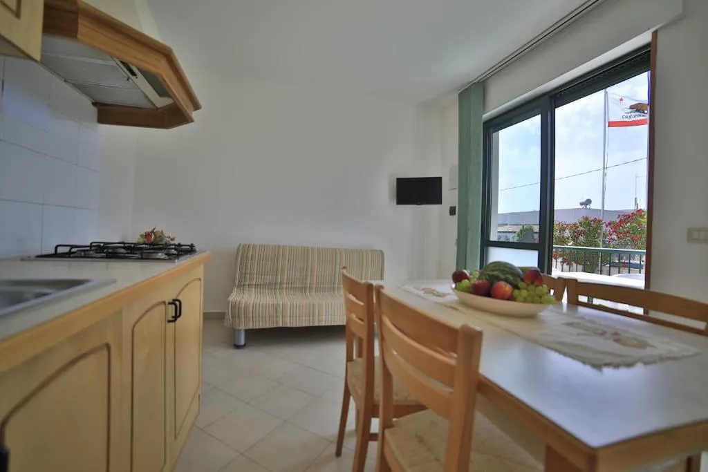 Cucina e zona pranzo con divano e ampia finestra sul balcone