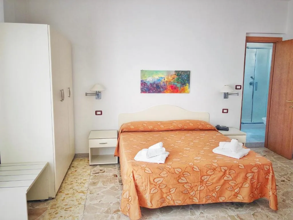 Camera con letto matrimoniale, armadio bianco e bagno con doccia attiguo