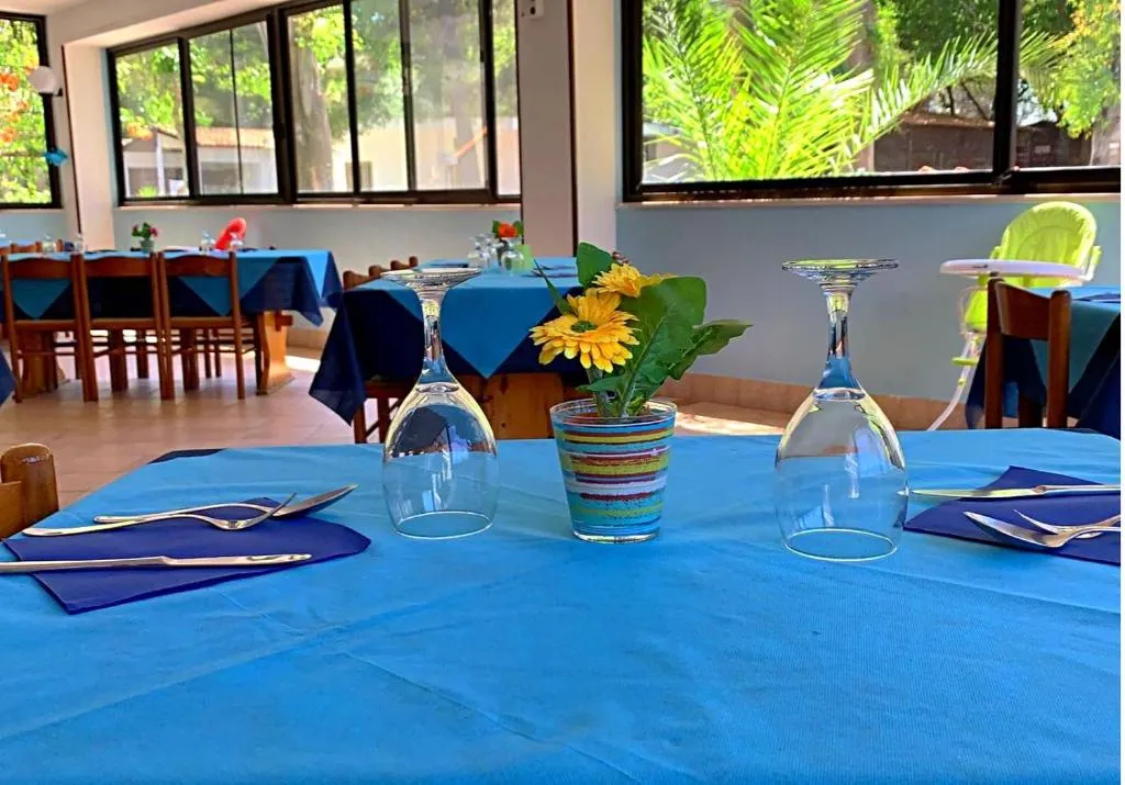 Tavolo del ristorante apparecchiato con tovaglia azzurra, bicchieri e fiori