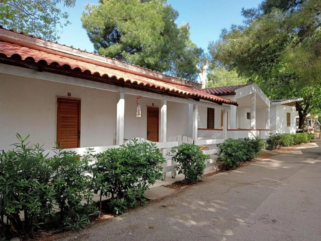Bungalow bianchi con tetto in tegole rosse lungo un vialetto alberato