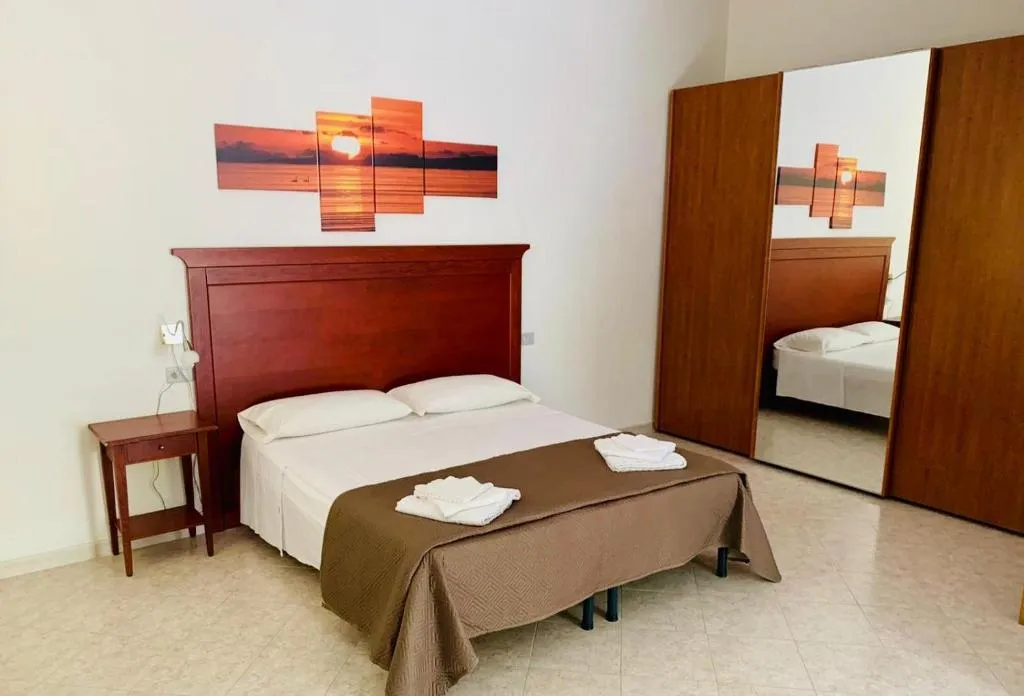 Camera da letto con letto matrimoniale, testiera in legno e armadio a specchio