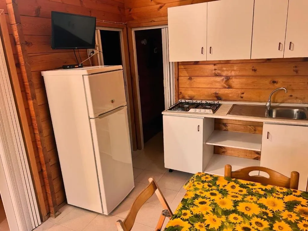Cucina di bungalow in legno con frigorifero, fornelli, lavello e TV